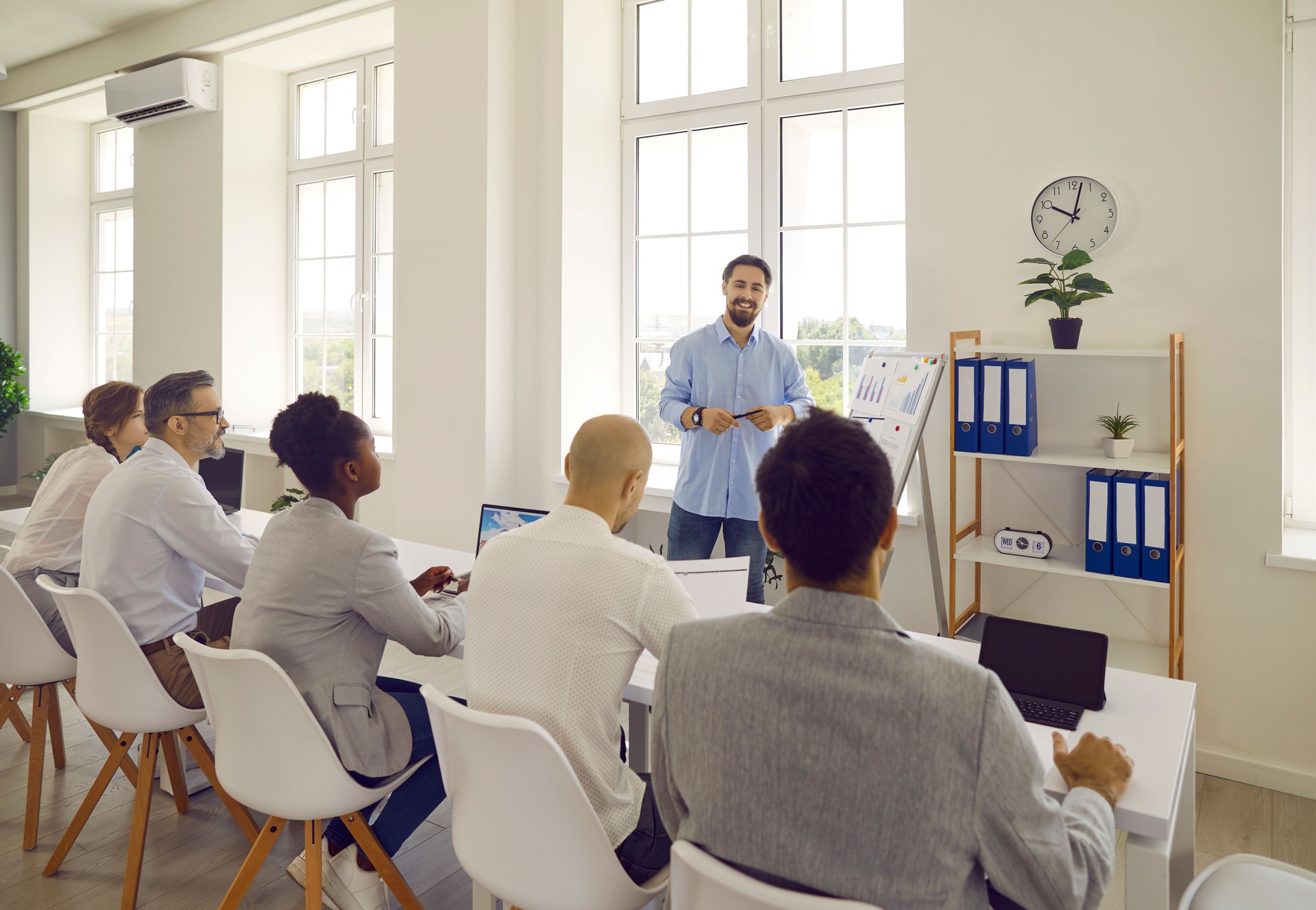 Man teacher business couch teaches communicates with a group of adult students in office.